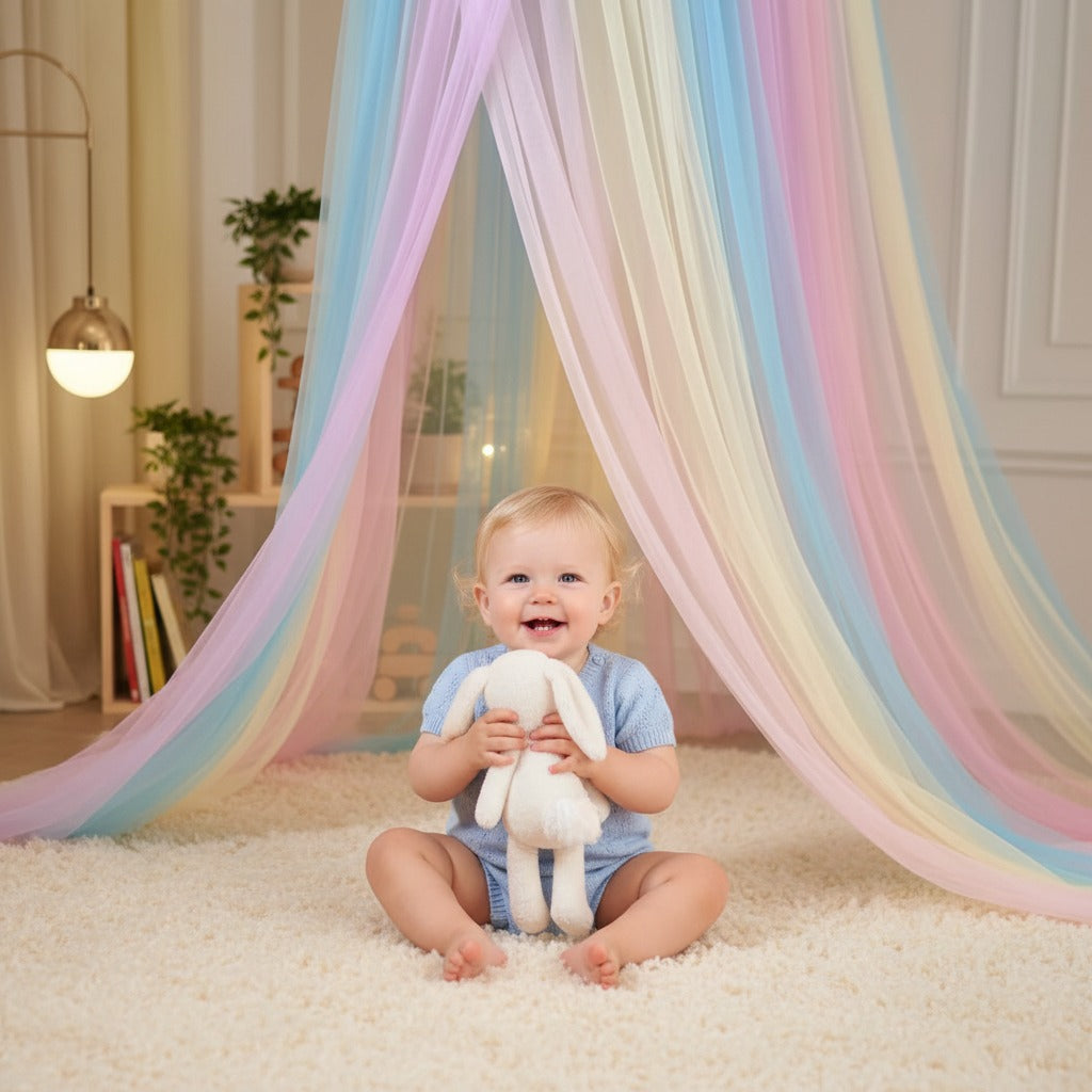 Bébé assit souriant sous Ciel de lit bébé Rêve Arc en Ciel