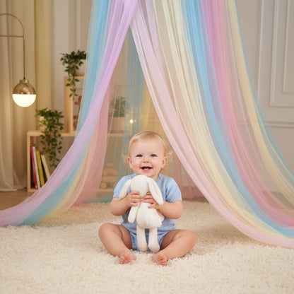 Bébé assit souriant sous Ciel de lit bébé Rêve Arc en Ciel