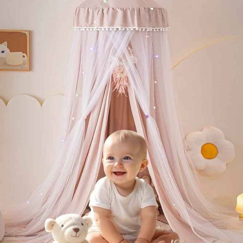 Bébé assit souriant sous Voile de lit bebe suspendu Cocon Apaisant