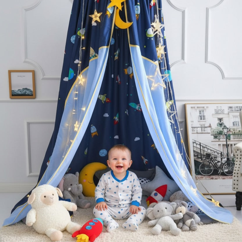 Bébé assit souriant sous ciel de lit bébé garçon spatial