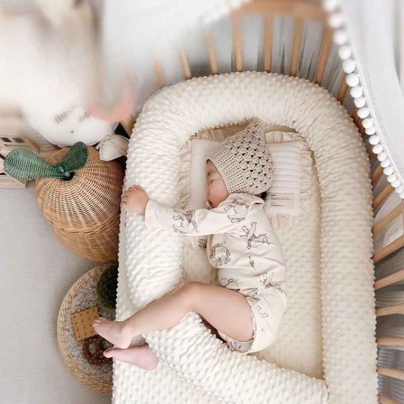 Bébé dormant paisiblement dans berceau avec un tour de lit pour bebe doux entre ses jambes Nid Protecteur