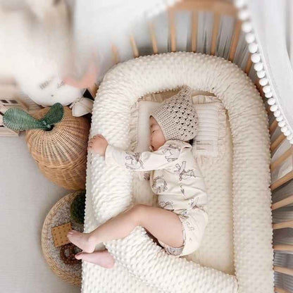 Bébé dormant paisiblement dans berceau avec un tour de lit pour bebe doux entre ses jambes Nid Protecteur