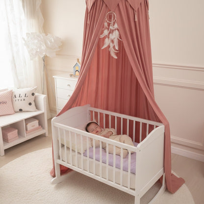 Bébé dort paisiblement dans berceau avec voile lit bebe terracotta