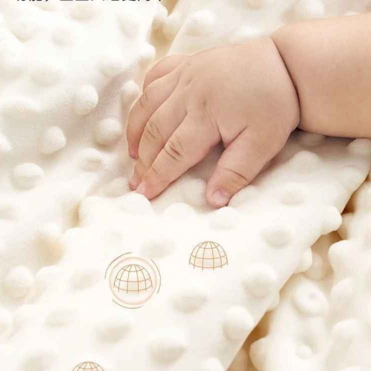 Main de bébé touchant la texture douce et bulbeuse d'un tour de lit bebe Nid Protecteur