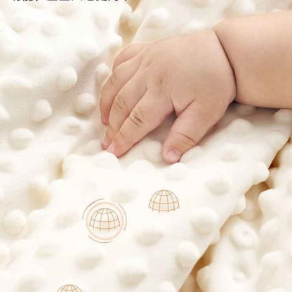 Main de bébé touchant la texture douce et bulbeuse d'un tour de lit bebe Nid Protecteur