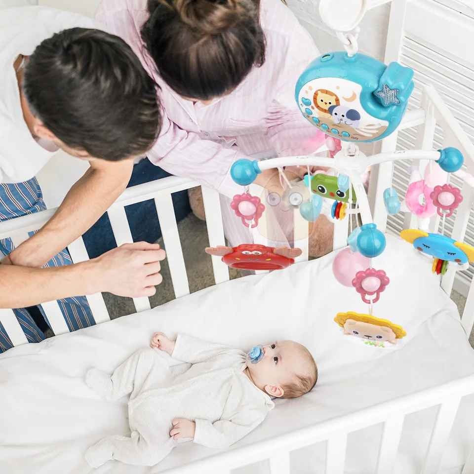Parents regardent bébé dans berceau avec mobile musical bébé Apaisant