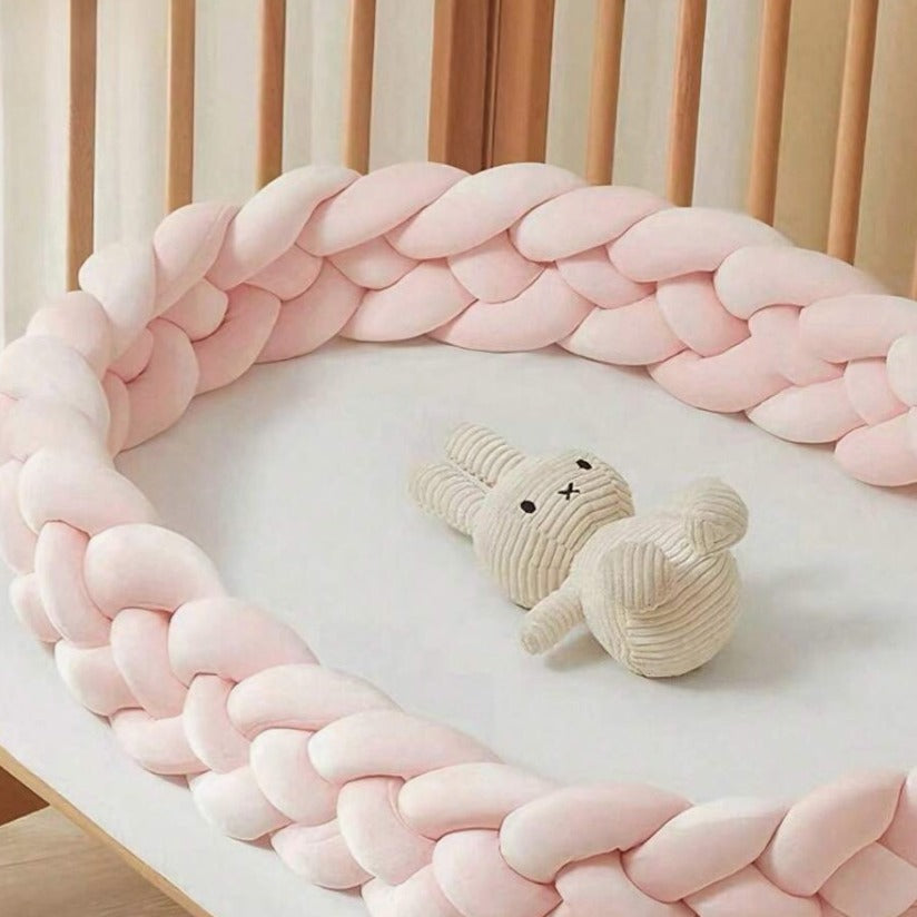 Tour de lit tressé rose autour une peluche lapin dans un berceau CozyBaby