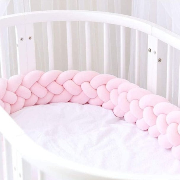 Tour de lit tressé rose fait le tour dans un berceau blanc CozyBaby