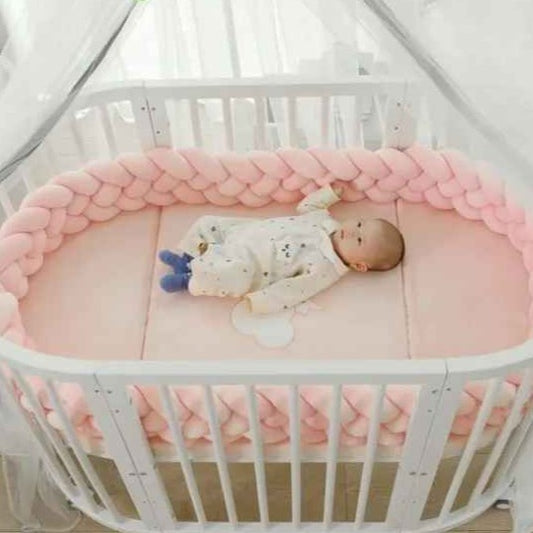 bébé dans un berceau ovale protége par tour de lit tressé rose CozyBaby