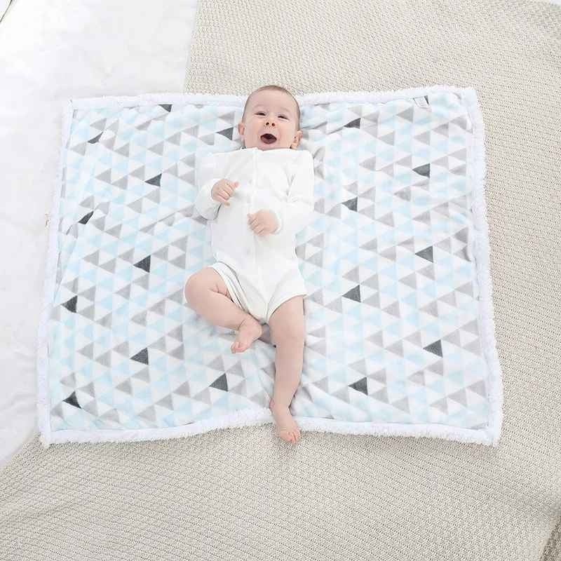 bébé souriant sur couverture bébé blanche triangle bleu chaudoudou