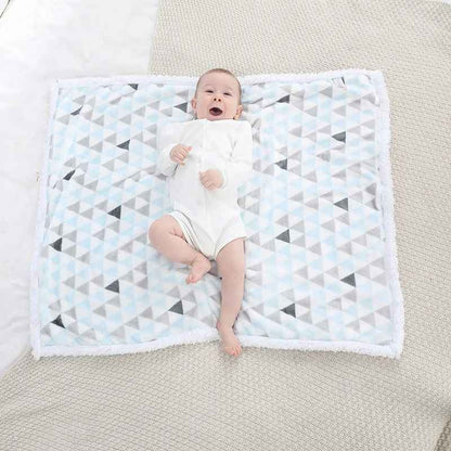 bébé souriant sur couverture bébé blanche triangle bleu chaudoudou
