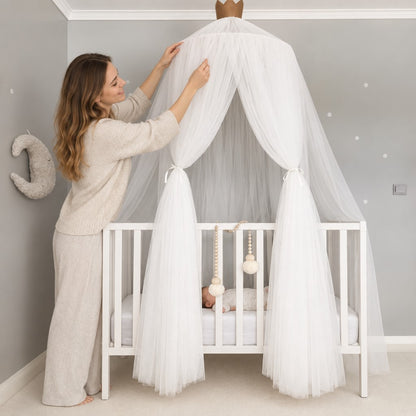 maman souriante ajustant le ciel de lit bebe voile au dessus du berceau Cocon Rêveur